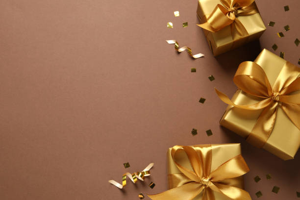 istock Beautiful golden gift boxes and confetti on brown background, flat lay. Space for text 1434435407