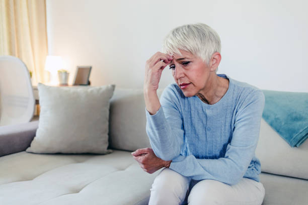 istock Sad depressed woman at home sitting on the couch, looking down and touching her forehead, loneliness and pain concept 1434435754