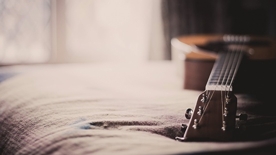 A selective focus of a guitar lying on bed