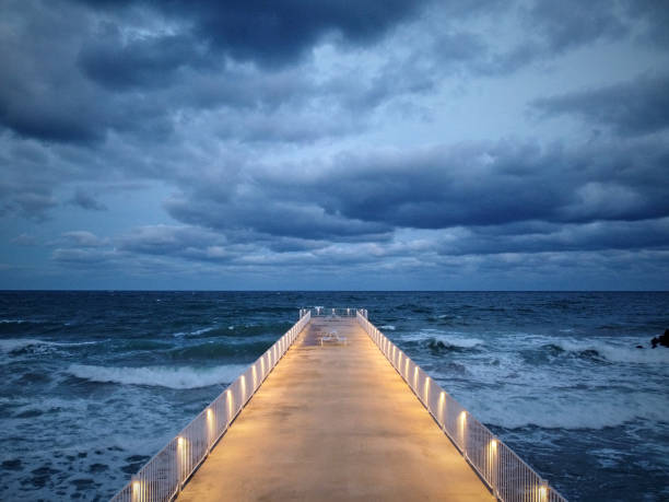 istock illuminated pier with dramatic sky over stormy dark sea at evening 1434437776