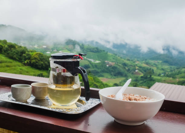 The breakfast set had pork porridge and a tea set side by side with mountains in the background and flares. stock photo