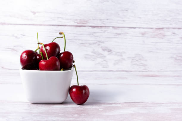 Set of cherries in a small white bowl and copy space