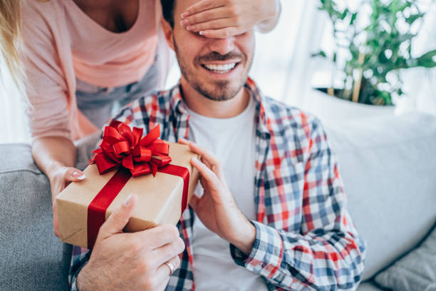 istock Cheerful young man receiving a gift from his girlfriend. 1434437990