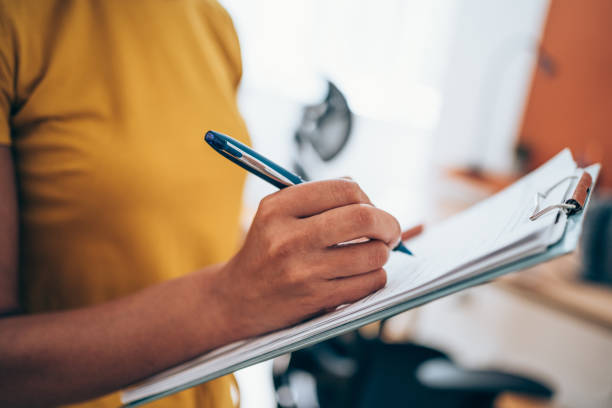 femme écrivant à la main sur le presse-papiers avec un stylo. - tracer photos et images de collection