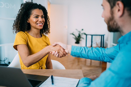 Shot of smiling business persons shaking hands after signing a contract. Business people shaking hands in the office. Photo of one cheerful businessman and one happy businesswoman handshaking.