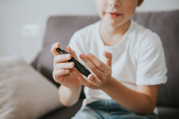 concepto de vida de un niño con diabetes y control glucémico. niño midiendo el nivel de azúcar en la sangre con un medidor de glucosa en sangre en casa, día mundial de la diabetes - photography ideas healthcare and medicine indoors fotografías e imágenes de stock