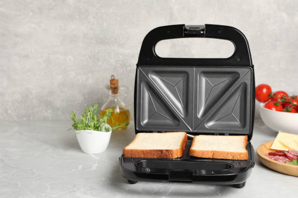 istock Modern sandwich maker with bread slices and different products on light grey table, space for text 1434440365