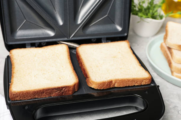istock Modern sandwich maker with bread slices on light grey table, closeup 1434440860