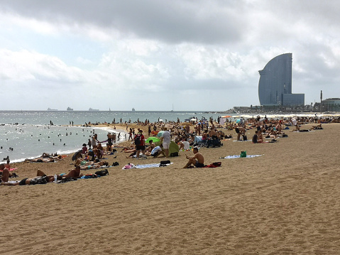 People sunbathing at Playa De Barceloneta, a sandy beach on the old quarter of Barceloneta, Barcelona, Spain.