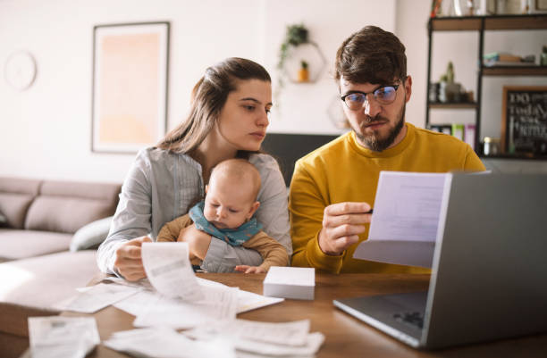Young family managing budget and paying bills and taxes. Young family with baby worried about family budget and high taxes and bills. Inflation concept. cost of living stock pictures, royalty-free photos & images