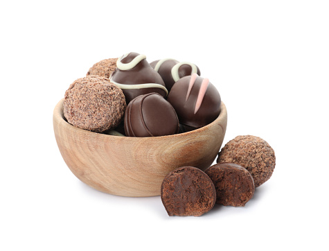 Bowl with many different delicious chocolate truffles on white background