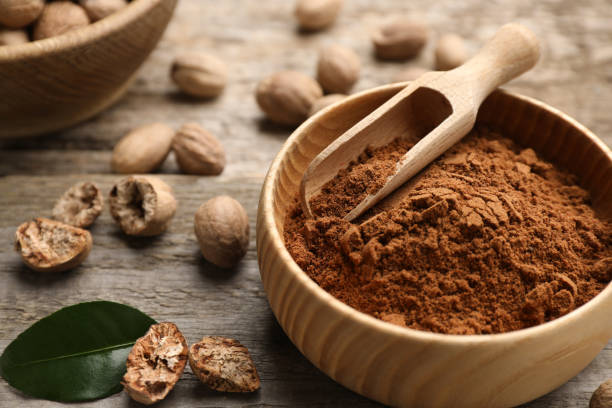 istock Nutmeg powder and seeds with green leaf on wooden table 1434447875