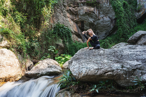 Asian women relax on the holiday. Play yoga at a waterfall on the mountain.