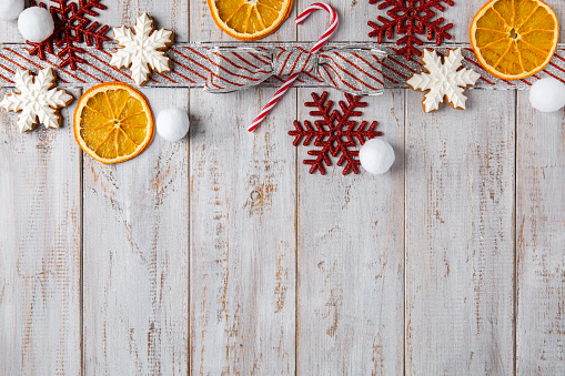 Christmas composition, arrangement of dry oranges, gingerbread cookies and x-mas bow on white wooden background. Top view, flat lay, copy space.