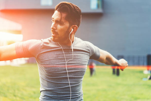 istock Muscular male athlete warming up and exercising during outdoors endurance workout, handsome Caucasian sportsman in modern earphones listening music while having training for keep fit body shape 1434456128