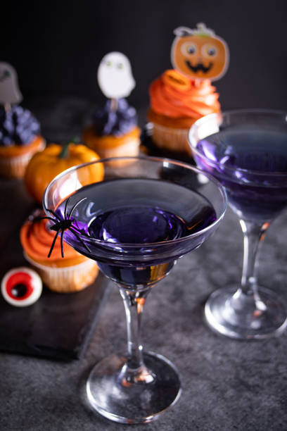 Halloween purple cocktail in glasses decorating spider. Nearby web, cupcakes and candy eyeball. Party festive celebrate concept. stock photo