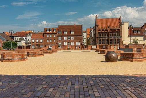 Germany, Wismar - July 13, 2022: Looking east from St. Marienkirchturm, St. Mary church tower over yellow grounds. Red and black brick buildings under blue cloudscape.