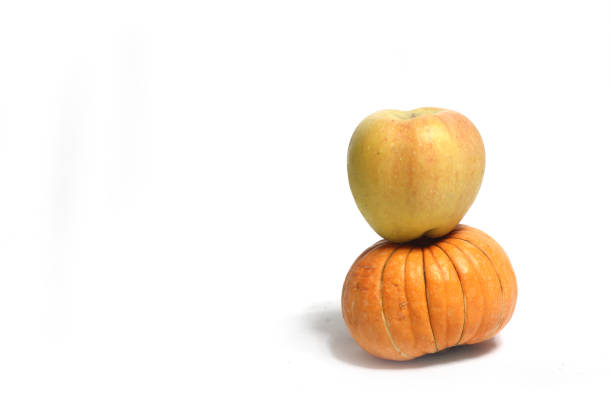 healthy eating concept - a pile of pumpkin and an apple against white background. Image contains copy space