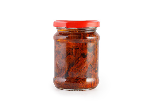 Sun dried tomatoes with olive oil in glass jar isolated on a white background, clipping path, cut out. Sun-dried tomatoes, preserves.