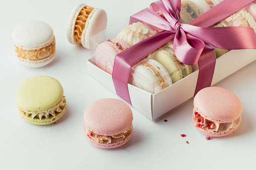 Gift white box full of multicolored macaroons on the white background. French dessert