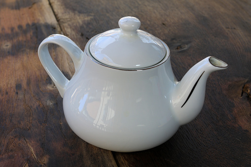white porcelain teapot on rustic wooden backdrop