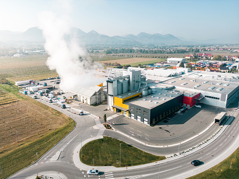 Aerial view of an industrial district with polluting factories and warehouse storages. Steam and smoke rising from industrial factories.