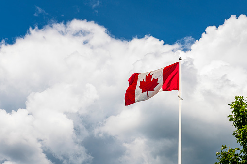 Flag of Canada flying against a blue sky. North America
