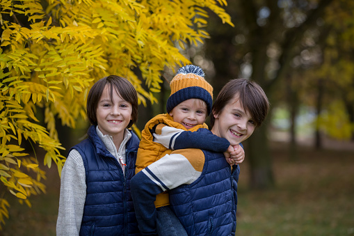 Happy family, mother with children, having their autumn pictures taken in the park, children playing
