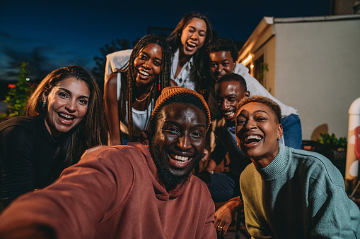 Multiethnic group of people are taking a selfie together during a dinner party. They are having fun together.
