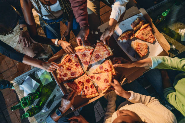 cena con amigos - vista de ángulo alto de personas tomando rebanadas de pizza - pizza de chorizo fotos fotografías e imágenes de stock