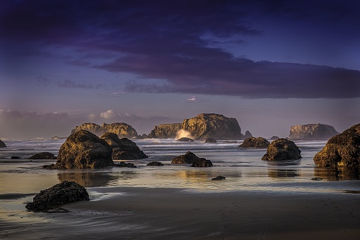 The sandy beach with big rocks and cliffs in the background in the ocean in Bandon city - suitable for a wallpaper