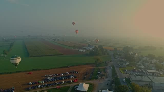 Drone View of Multiple Hot Air Balloons Looking for Landing Sites on a Foggy Morning
