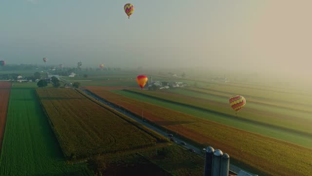Drone View of Multiple Hot Air Balloons Looking for Landing Sites on a Foggy Morning