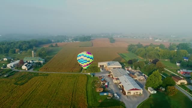 Drone View of a Single Hot Air Balloon Launching Near a Farm and Business