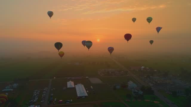 Drone View of Multiple Hot Air Balloons Getting Ready to Launch on a Foggy Morning