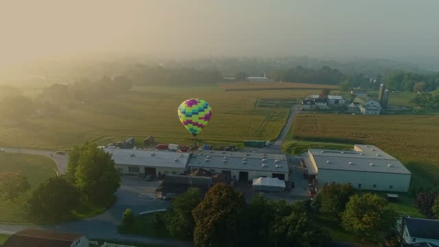 Drone View of a Single Hot Air Balloon Landing Near a Farm and Business