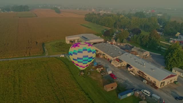 Drone Circling View of a Single Hot Air Balloon Landing Near a Farm and Business