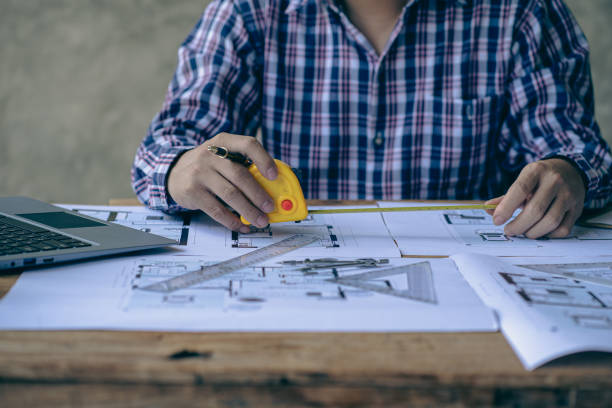 istock A close-up view of engineers drawing plans and measurements at work. Architects design, work, draw, sketch, and model architectural construction in the home. 1434497633