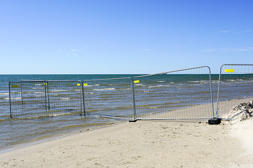 A temporary prefabricated metal mesh fence on the seashore extends into the water, territory delimitation