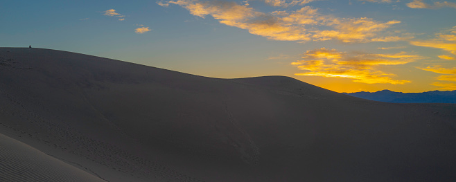 Sunset over the sand dune mountains. Mesquite Flat Sand Dunes and abstract geometry of curving silhouette desert hills at sunset in Death Valley National Park, California