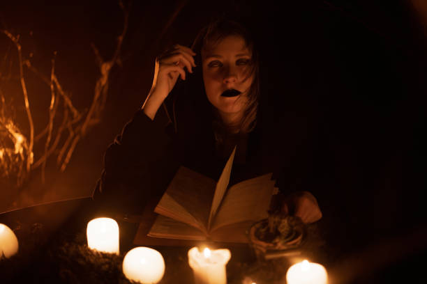 istock Young beautiful witch in a black robe looking at the camera. Halloweens horror. Scary tale. Halloween's concept of Night fairy tale. 1434505749