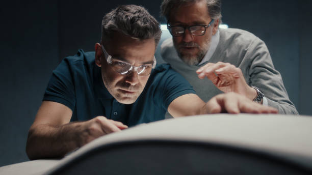 Design engineer with safety goggles makes design corrections in sculpture of car Design engineer with safety goggles works on the sculpture of a prototype car model using a pen type tool. Making design corrections and perfecting it while discussing with a colleague. industrial designer stock pictures, royalty-free photos & images