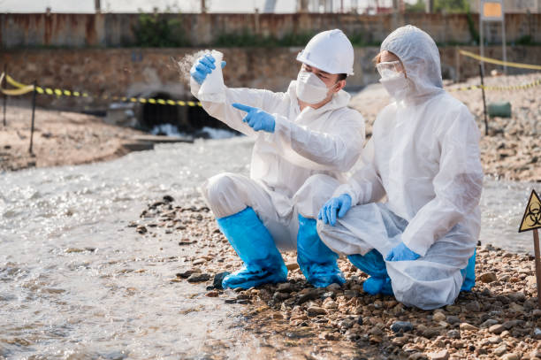 die ökologen des teams untersuchen abwasser mit ph-testergebnissen von wasser, das aus rohren von raffinerien in die natur eingeleitet wird, um eine biogefahr durch chemische kontamination zu vermeiden. - medical waste stock-fotos und bilder