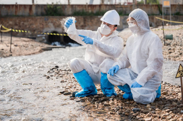 チームの生態学者は、化学汚染バイオハザードを防ぐために、製油所のパイプから自然に排出された水のph試験結果で廃水を調べます。 - medical waste ストックフォトと画像