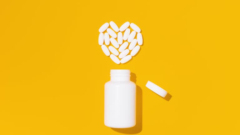 White pills in heart shape with bottle on yellow background. Mockup for advertising or other ideas. Medical and healthcare concept. Stop Motion Animation.