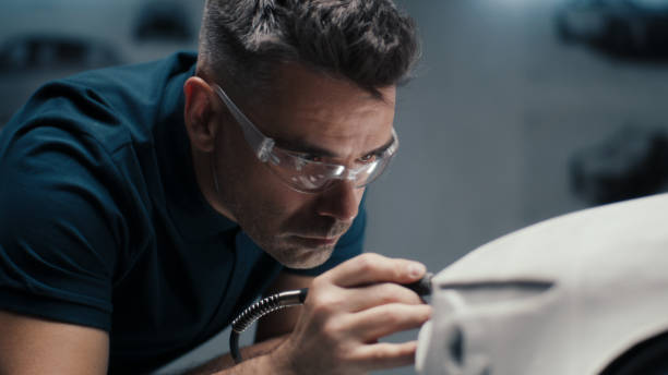 Automotive engineer with safety goggles uses a pen tool for perfecting car model Senior automotive design engineer uses a rotary tool for perfecting the rake sculpture of a car model in a high tech company. Engineer wearing safety goggles works in an automotive company. industrial designer stock pictures, royalty-free photos & images