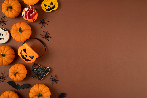 Halloween decorations, pumpkins, bats, ghosts on brown background with copy space