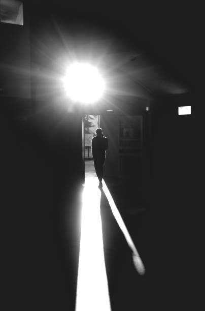istock Vertical shot of a man walking onto an open door while sun is reflecting over his shadow 1434510029