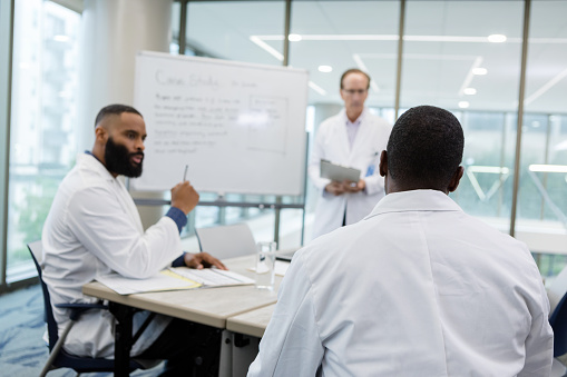 The three male doctors meet in the hospital conference room to brainstorm ideas to treat an especially difficult case.