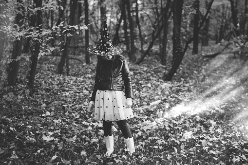 Little girl with witches hat hiding in the woods. Note for inspection; hat is not branded by any company, random hat.